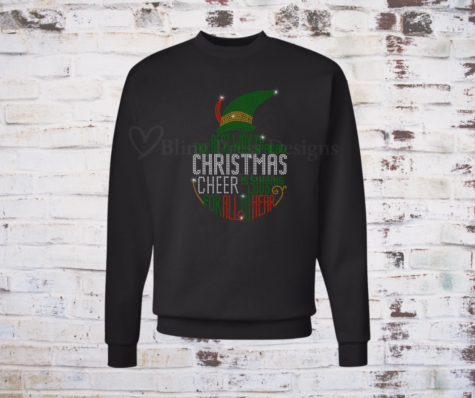 A festive black sweatshirt featuring a sparkling rhinestone design of a cheerful Christmas elf, accented with holiday-themed details. The bling embellishments catch the light, adding a glamorous touch to the holiday spirit.