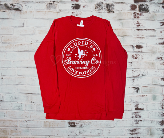 A festive long sleeve tee featuring a "Cupid's Brewing Company" design, made from soft, comfortable fabric with a unisex fit, perfect for celebrating Valentine's Day in style.