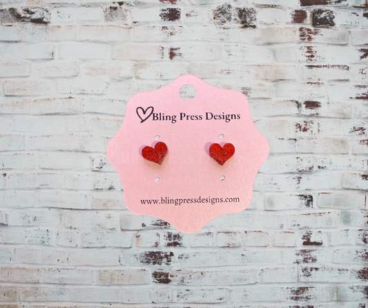 A pair of small glitter heart stud earrings with a sparkling finish, lightweight and stylish, perfect for everyday wear or special occasions.