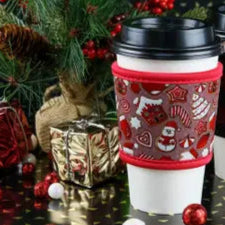 A reusable hot beverage sleeve designed to protect hands from hot drinks, featuring a holiday cookie design and lightweight, eco-friendly material that fits most coffee cups and tumblers.