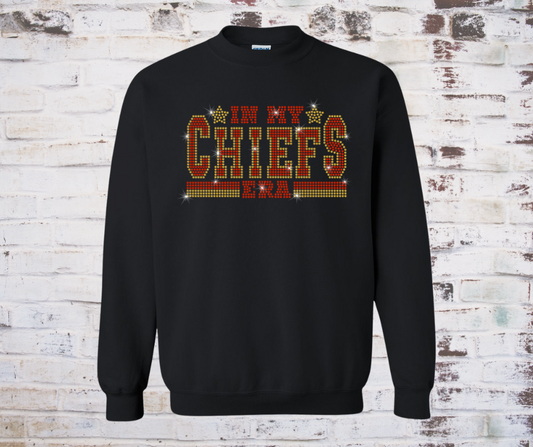 Shirt featuring a sparkling rhinestone design with the phrase “In My Chiefs Era.” The red and gold rhinestones shimmer brightly, creating a fun and spirited look perfect for Kansas City Chiefs fans.