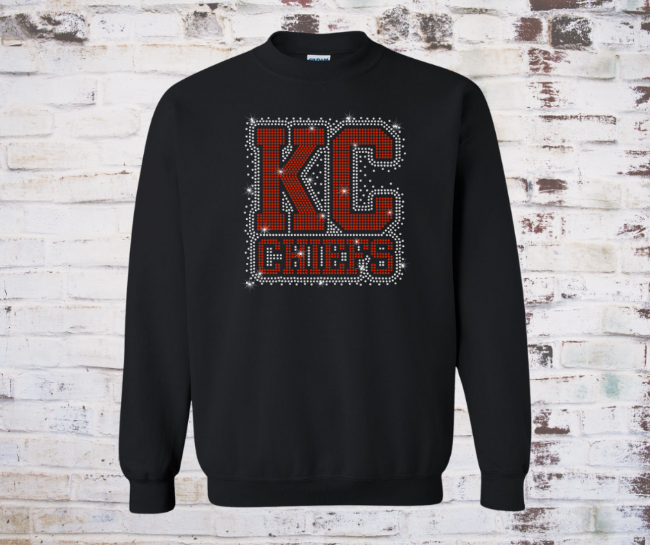 Shirt covered in sparkling rhinestones featuring a full KC Chiefs scatter design. The red, gold, and clear rhinestones shimmer across the entire shirt, creating a bold and eye-catching game day look full of team spirit.