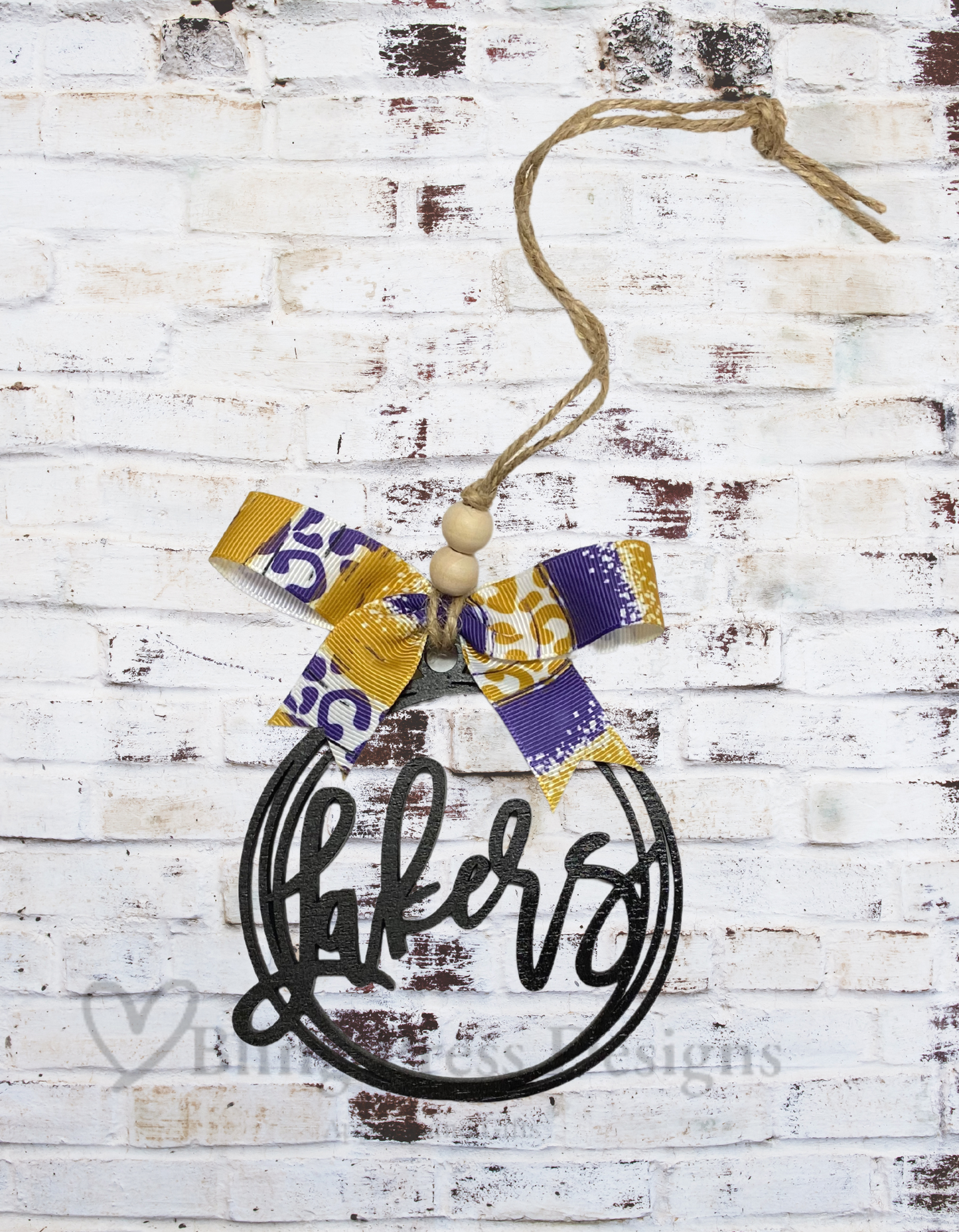 Wooden 4-inch round Lakers laser-cut car charm decorated with a purple and gold team-colored bow, designed to hang as an accessory.