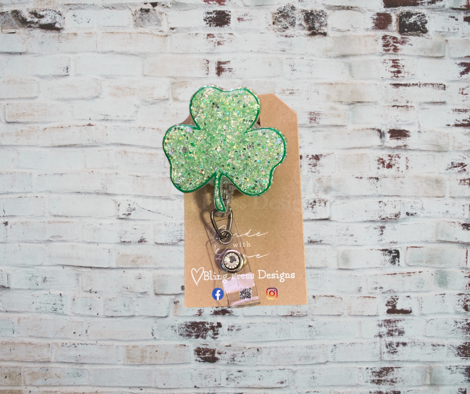 A handmade glitter badge reel with an interchangeable top, featuring a retractable cord and secure clip, perfect for adding sparkle and personality to work attire.