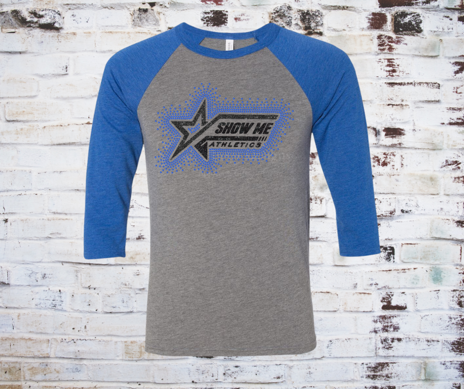 A rhinestones surrounding Show Me Athletics logo on a contrast colored 3/4 sleeve raglan tee, showcasing a comfortable fit with a touch of sparkle