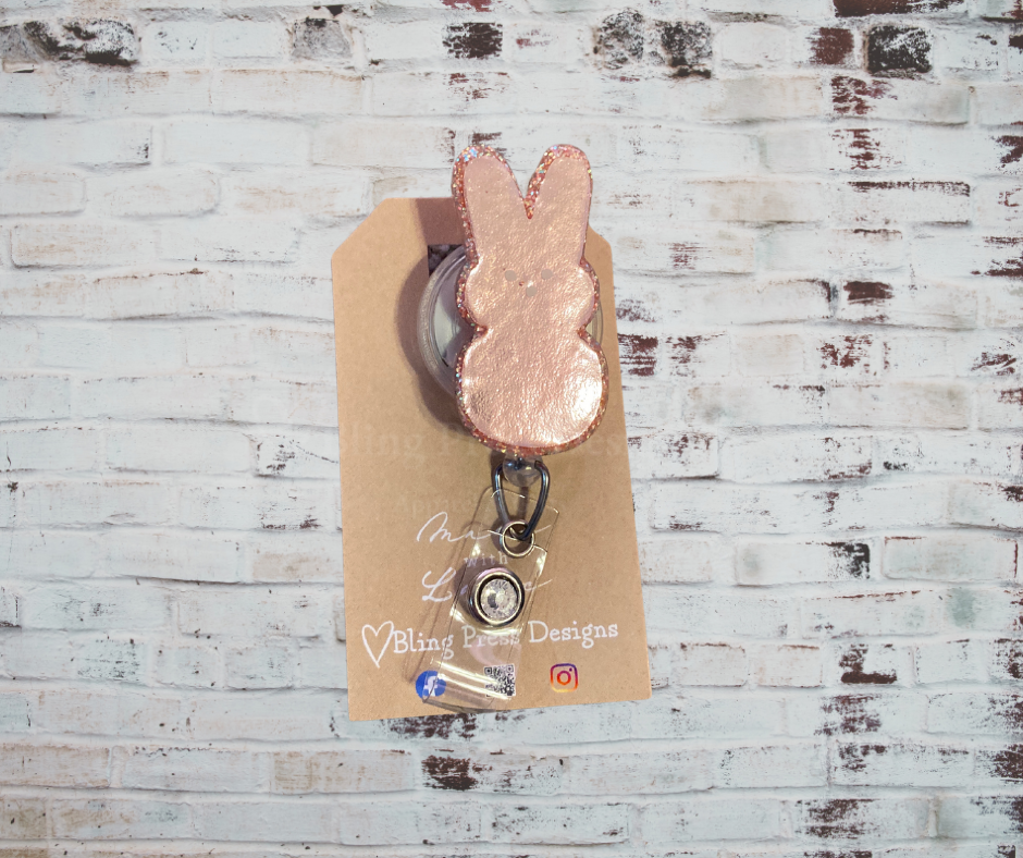 A handmade glitter badge reel with an interchangeable top, featuring a retractable cord and secure clip, perfect for adding sparkle and personality to work attire.