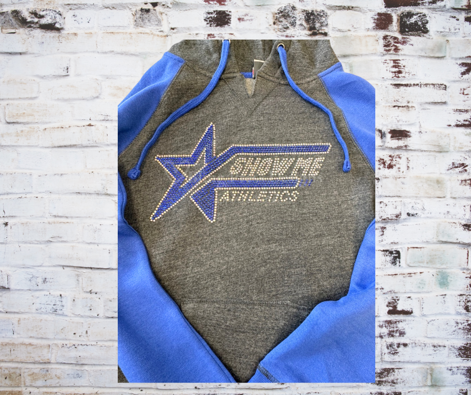 Close-up of a rhinestone-embellished 'Show Me Athletics' logo on a cozy hoodie, with sparkling rhinestones highlighting the bold logo design