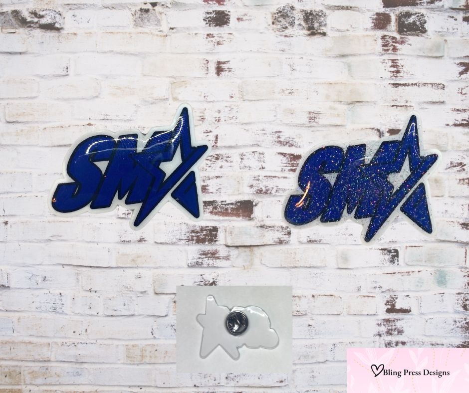 SMA logo hat pin available in two styles — one with glitter for extra sparkle and one without for a classic look.