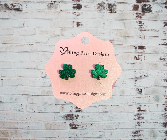 A pair of glitter shamrock acrylic stud earrings with a sparkling finish, lightweight and comfortable, perfect for St. Patrick's Day or adding a festive touch to any outfit.