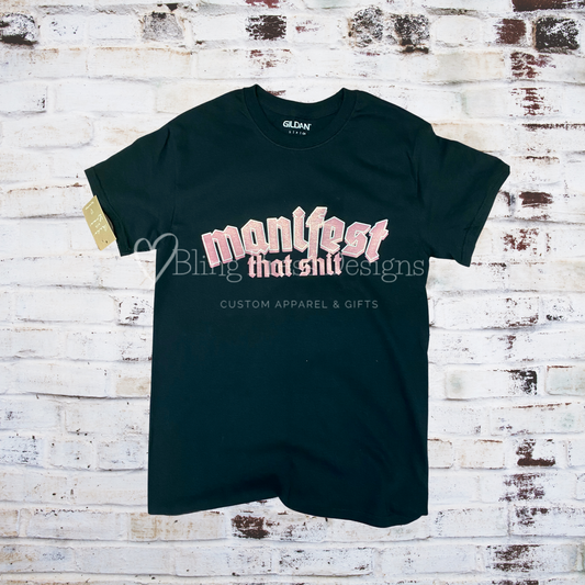 Glitter screenprinted tee with the phrase “Manifest That Shit” in bold, sparkly lettering.