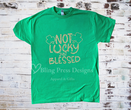 A Not Lucky Just Blessed St. Patrick's Day tee with a glitter vinyl design, featuring shimmering lettering on soft, breathable fabric. A fun and stylish way to celebrate the holiday with comfort and sparkle.