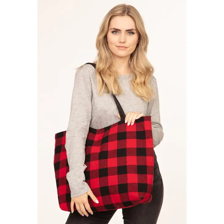 A woman carrying a red and black buffalo plaid zipper tote bag with spacious interior, sturdy construction, and comfortable straps, perfect for everyday use or adding a cozy touch to seasonal outings.