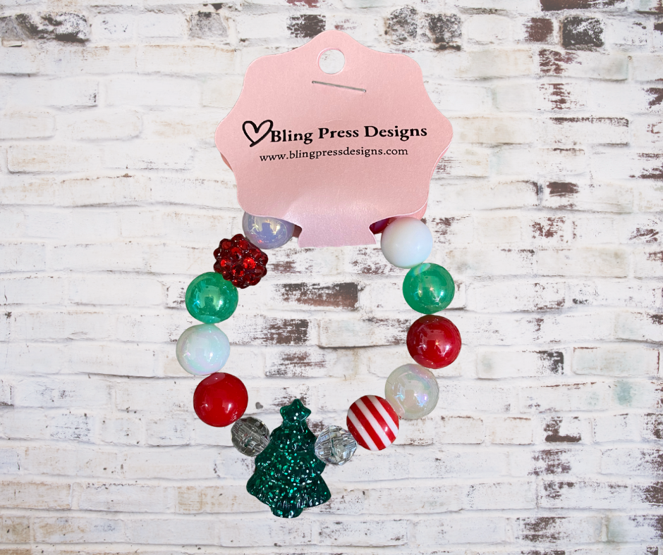 Colorful kids holiday stretch bracelets made with large bubble gum beads and festive charms, including Christmas-themed designs.
