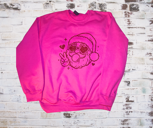 Hot pink sweatshirt featuring a red glitter Santa wearing heart-shaped sunglasses and blowing a pink bubblegum bubble.
