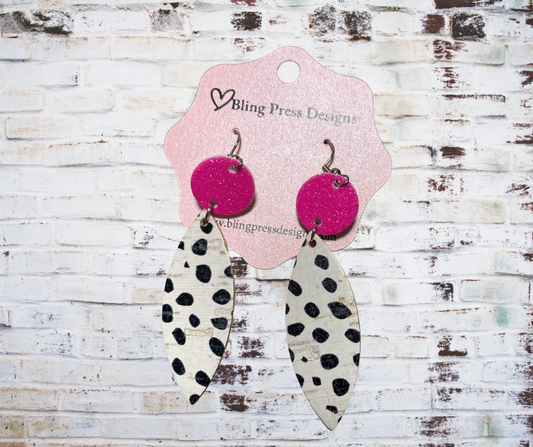 Pair of earrings with pink circular tops and black and white leaf-shaped bottoms on a Bling Press Designs card.