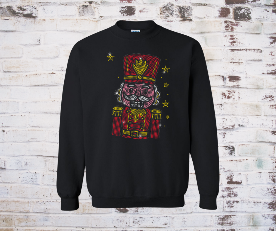 Black sweatshirt with a colorful rhinestone nutcracker design on a brick wall background