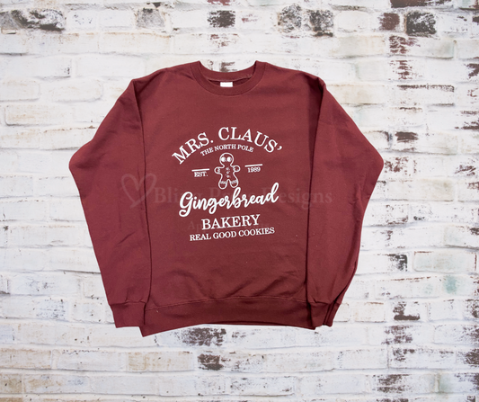 
Holiday sweatshirt with a festive print that reads “Mrs. Clause Gingerbread Bakery” featuring Christmas-themed design details.
