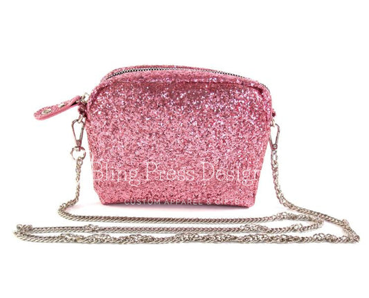 A small pink glitter purse with a metal chain strap, featuring a sparkling finish and compact design, perfect for carrying essentials to a night out or special event.