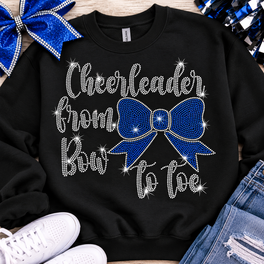  Cheerleader from Bow to Toe rhinestone design featuring sparkling silver lettering and a royal blue bow on a black Gildan Softstyle T-shirt, customizable to match team colors