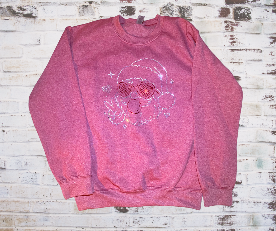 Rhinestone Santa sweatshirt featuring Santa wearing heart-shaped sunglasses and blowing a pink bubblegum bubble; sparkling rhinestone details add festive shimmer.