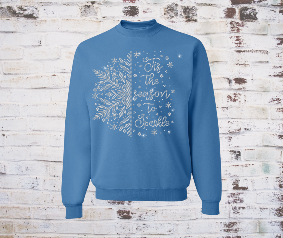 Blue sweatshirt with rhinestone snowflake design and text on a brick wall background