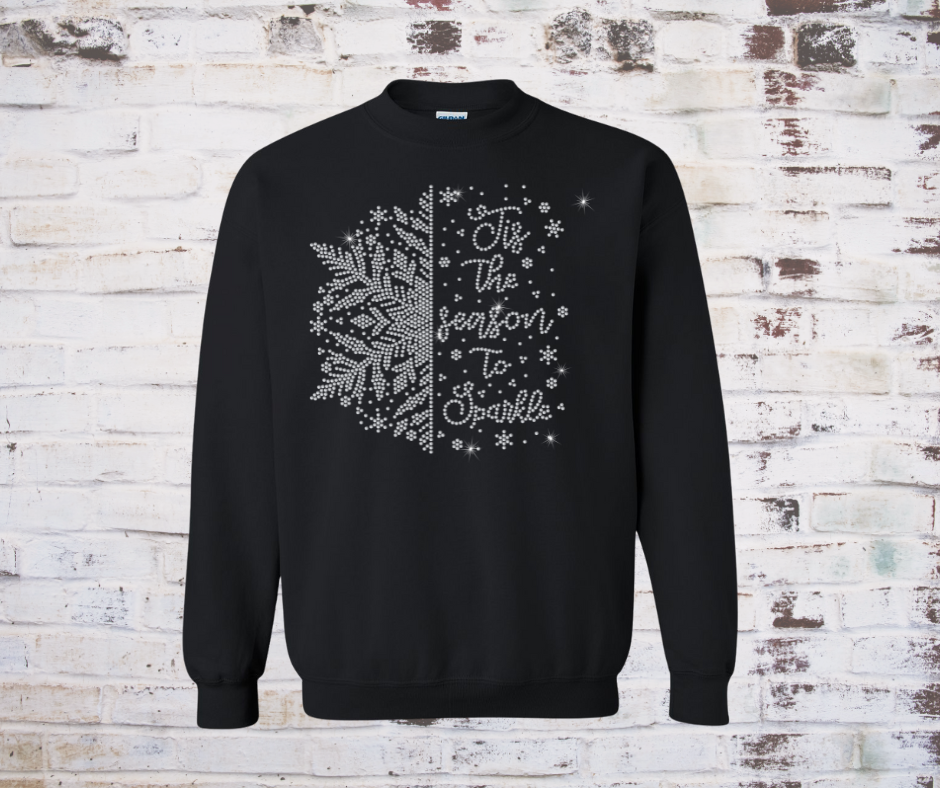 Black sweatshirt with rhinestone snowflake design and text on a rustic wooden background