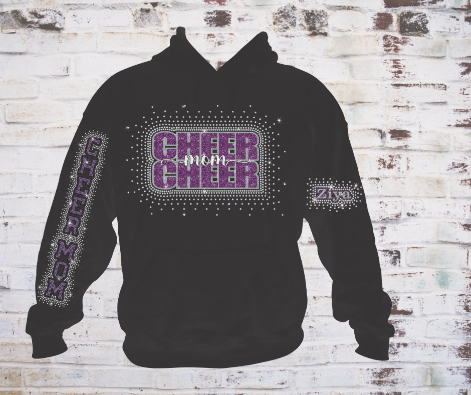 Black cheer mom shirt featuring a rhinestone “Cheer Mom” design on the front, with optional rhinestone sleeve upgrades including “Cheer Mom” on one sleeve and the athlete’s name with rhinestone scatter on the other sleeve.