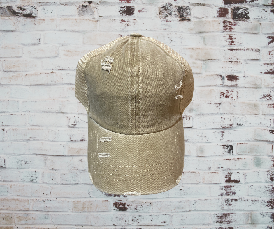 A distressed criss cross ponytail hat with a breathable design, adjustable Velcro strap, and elastic back openings for high, mid, or low ponytails, perfect for casual wear and customization.