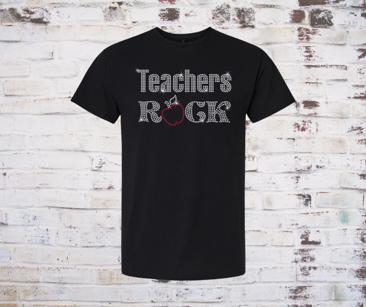 Black t-shirt with 'Teachers Rock' rhinestone with apple text on a rustic wooden background