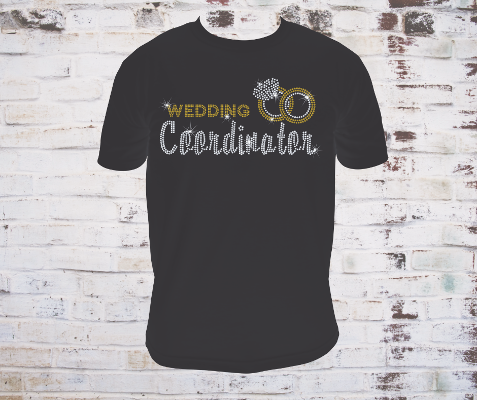 Black t-shirt with 'Wedding Coordinator' rhinestone text and rings design on a brick wall background
