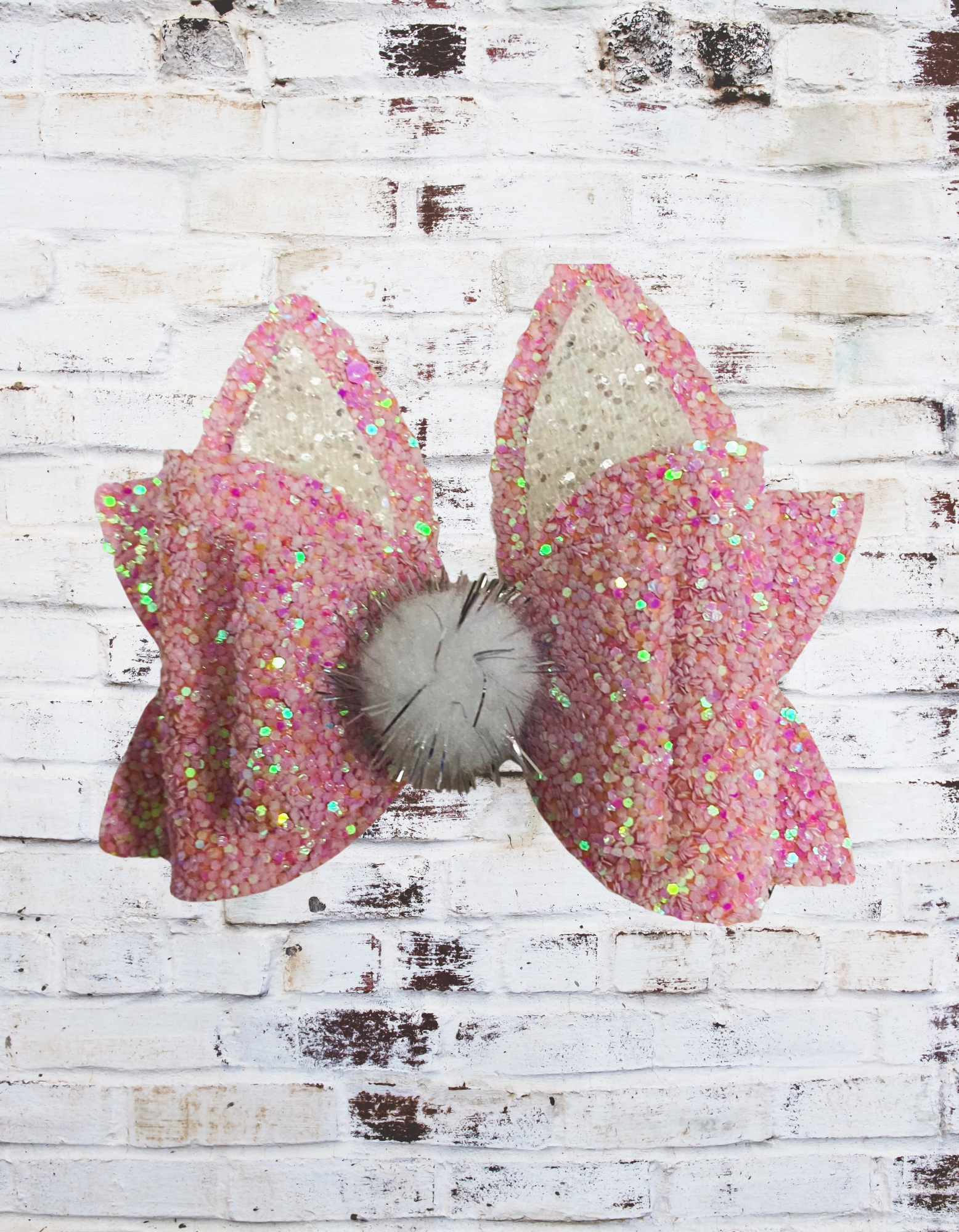 A pink glitter bunny hair bow with a sparkling finish, securely attached to an aligator clip, perfect for Easter outfits and festive hairstyles.
